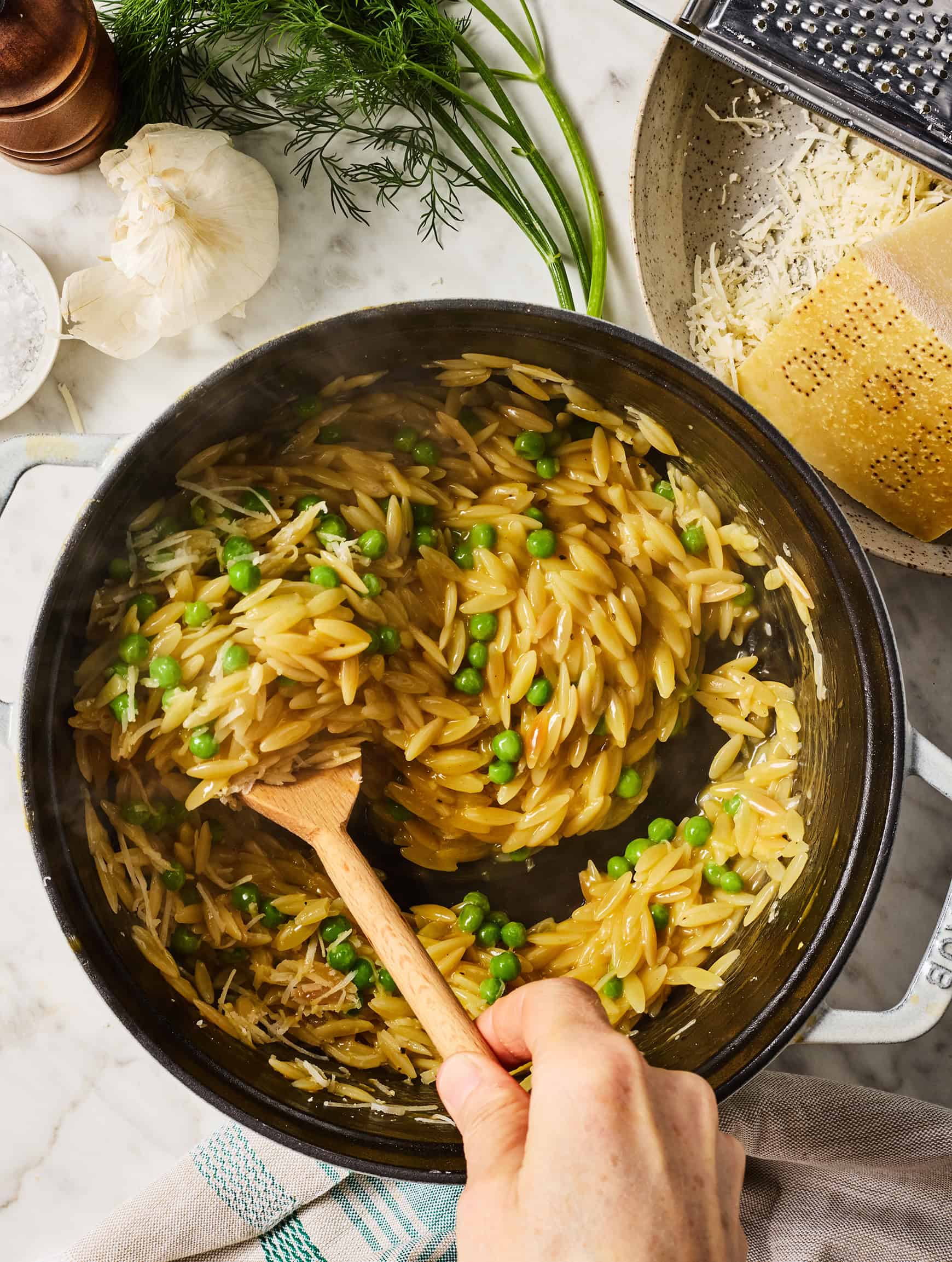 Stirring orzo and peas in Dutch oven