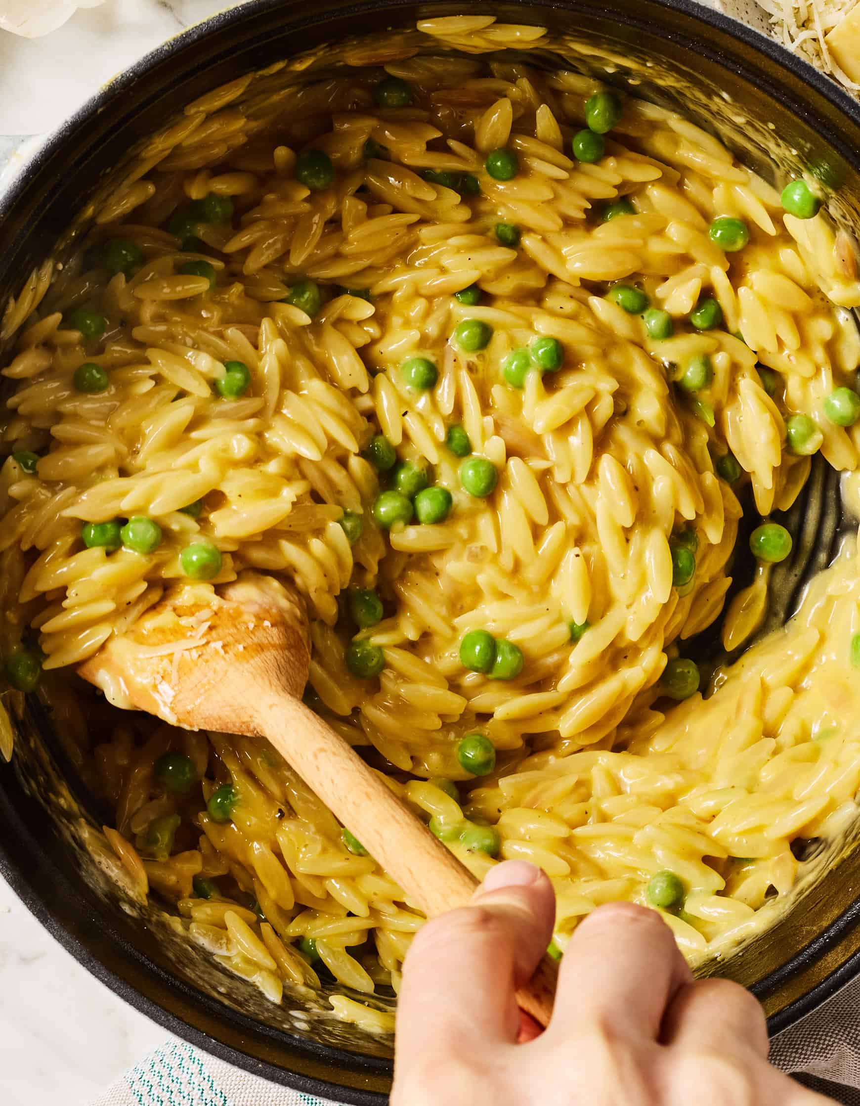 Stirring creamy lemon orzo pasta in pot