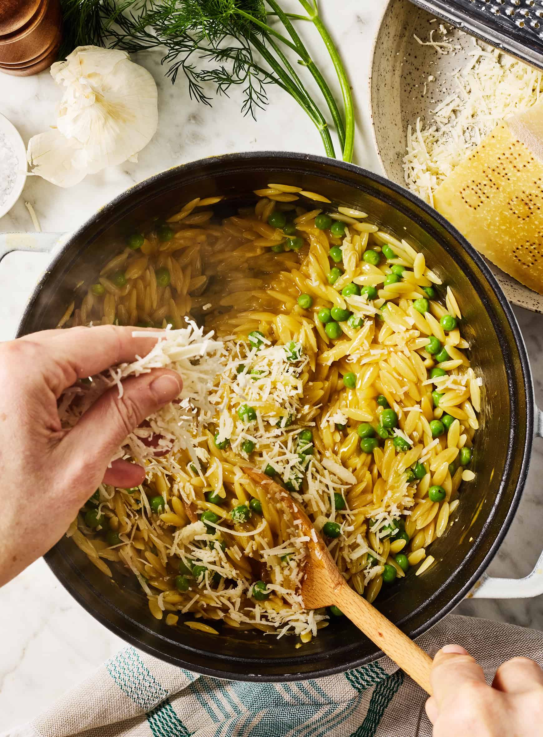Adding cheese to pasta mixture in pot