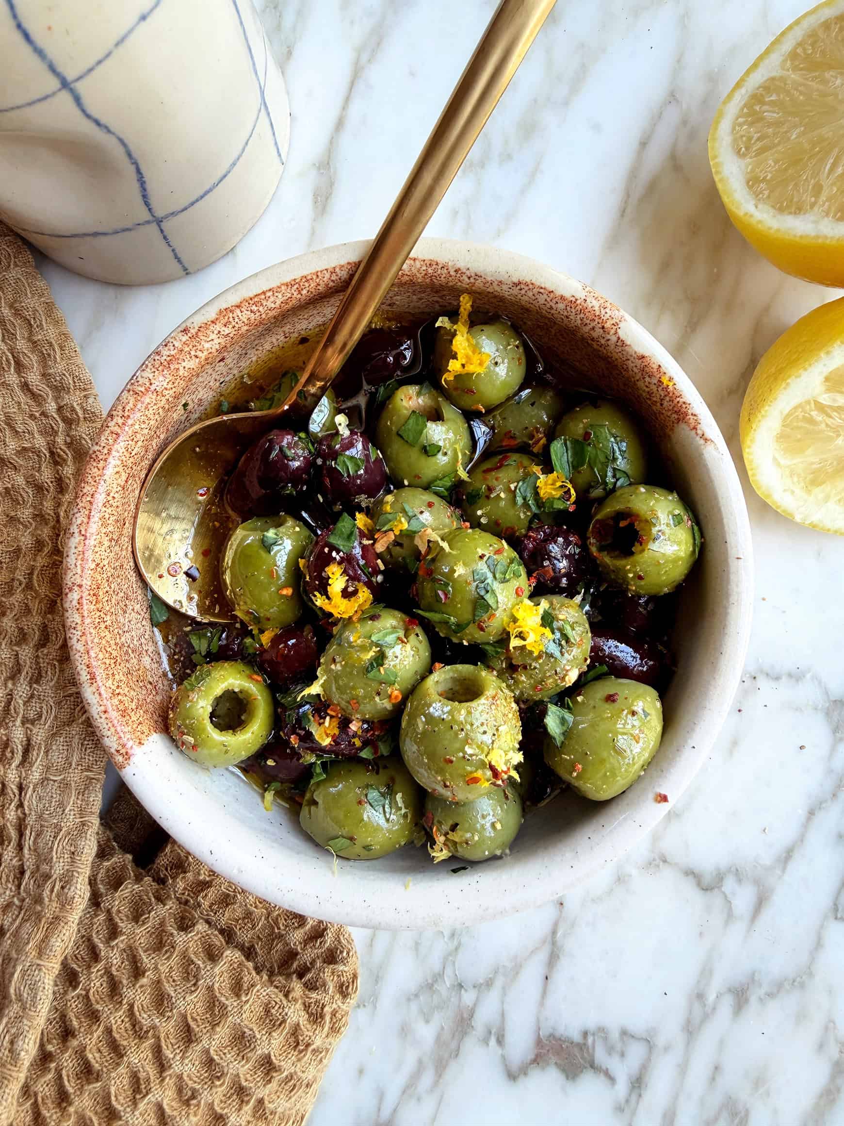 Marinated olives in small bowl with spoon