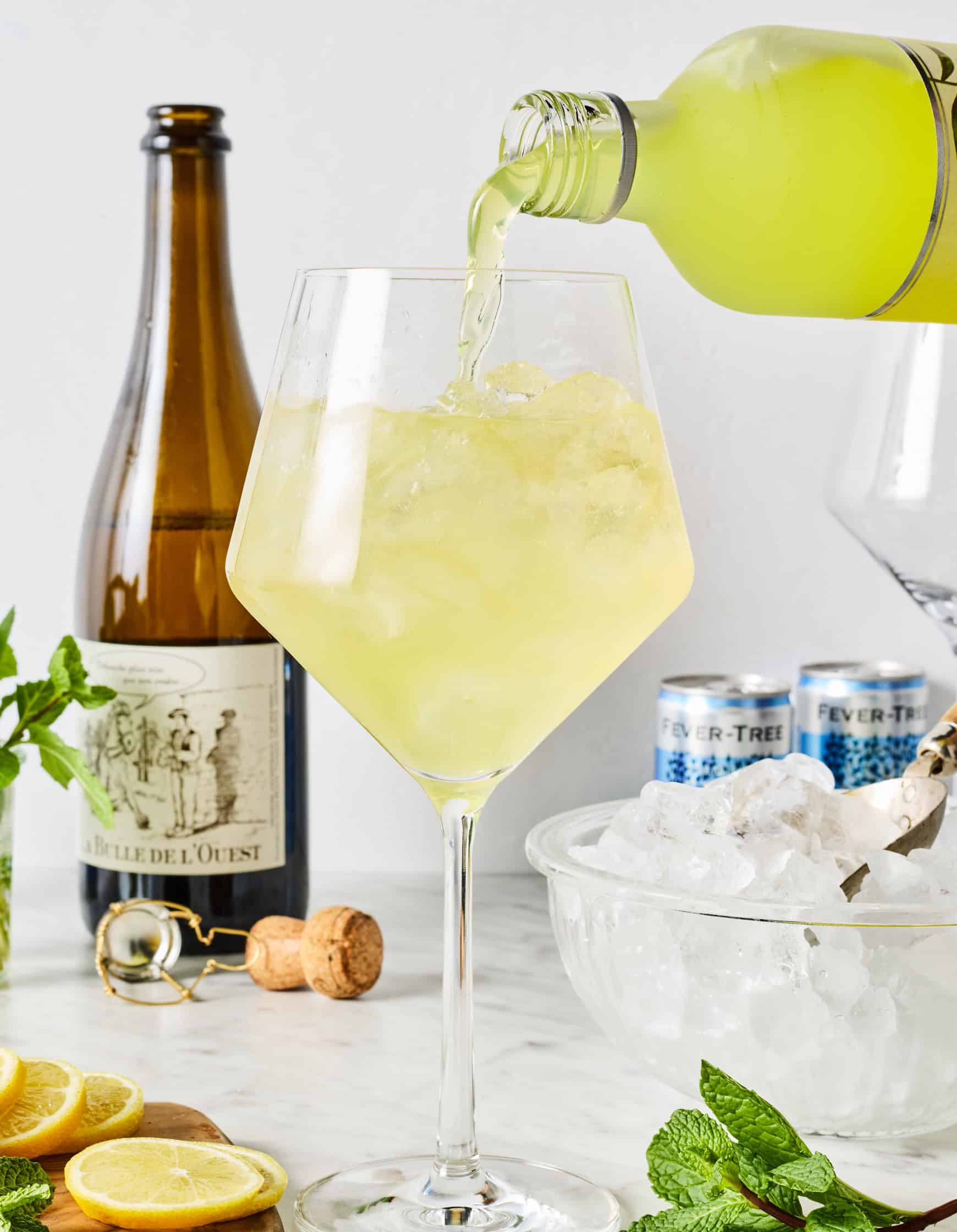 Pouring limoncello into large wine glass with ice