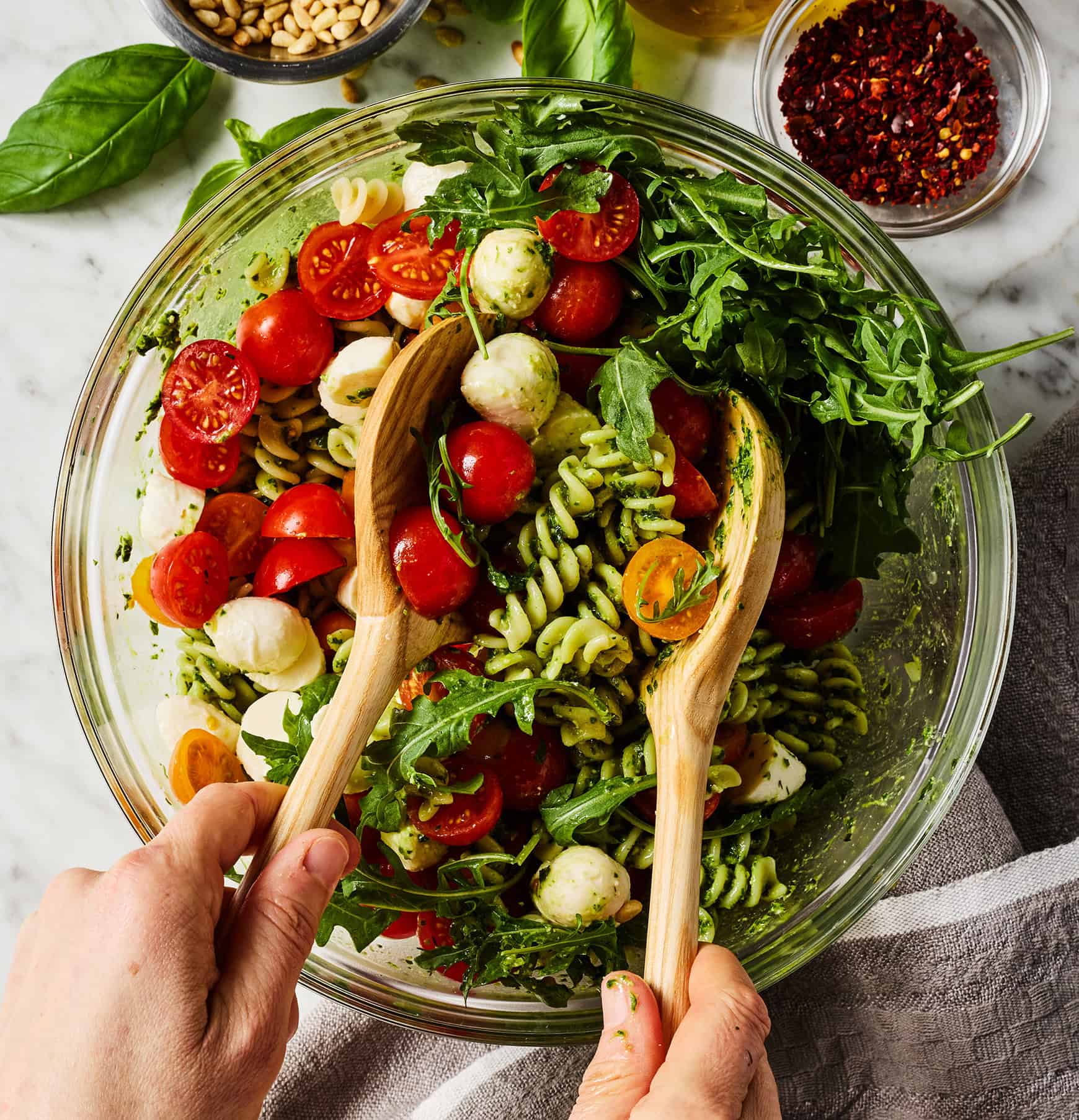 Tossing pesto pasta salad together in glass bowl