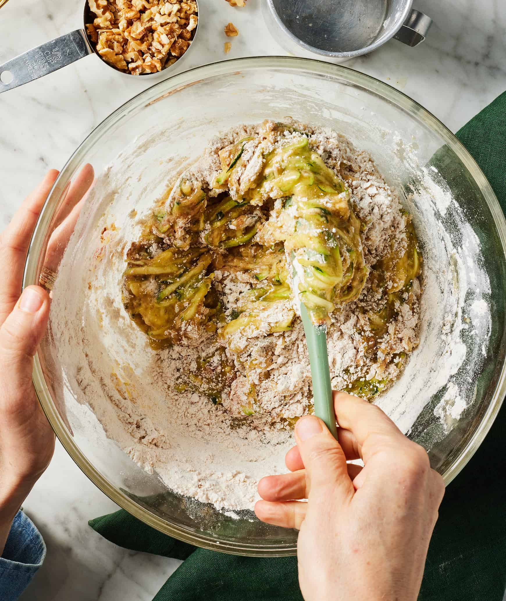 Mixing zucchini muffin batter with spatula