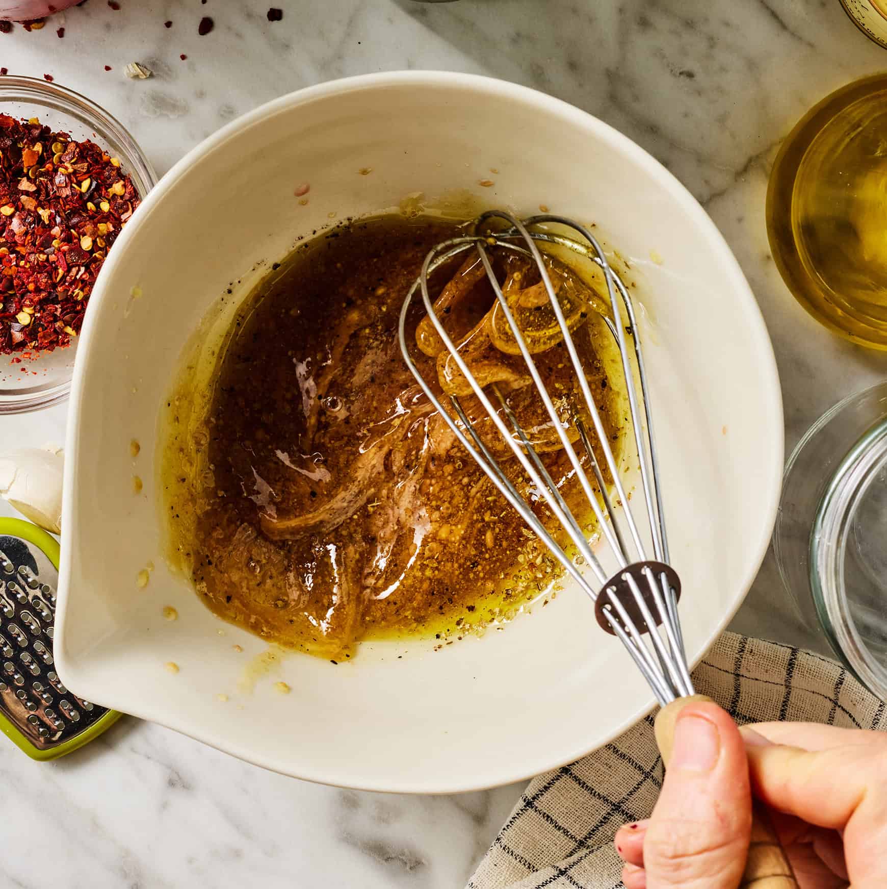 Whisking olive oil, red wine vinegar, Dijon mustard, honey, garlic, salt, pepper, and dried oregano in medium bowl