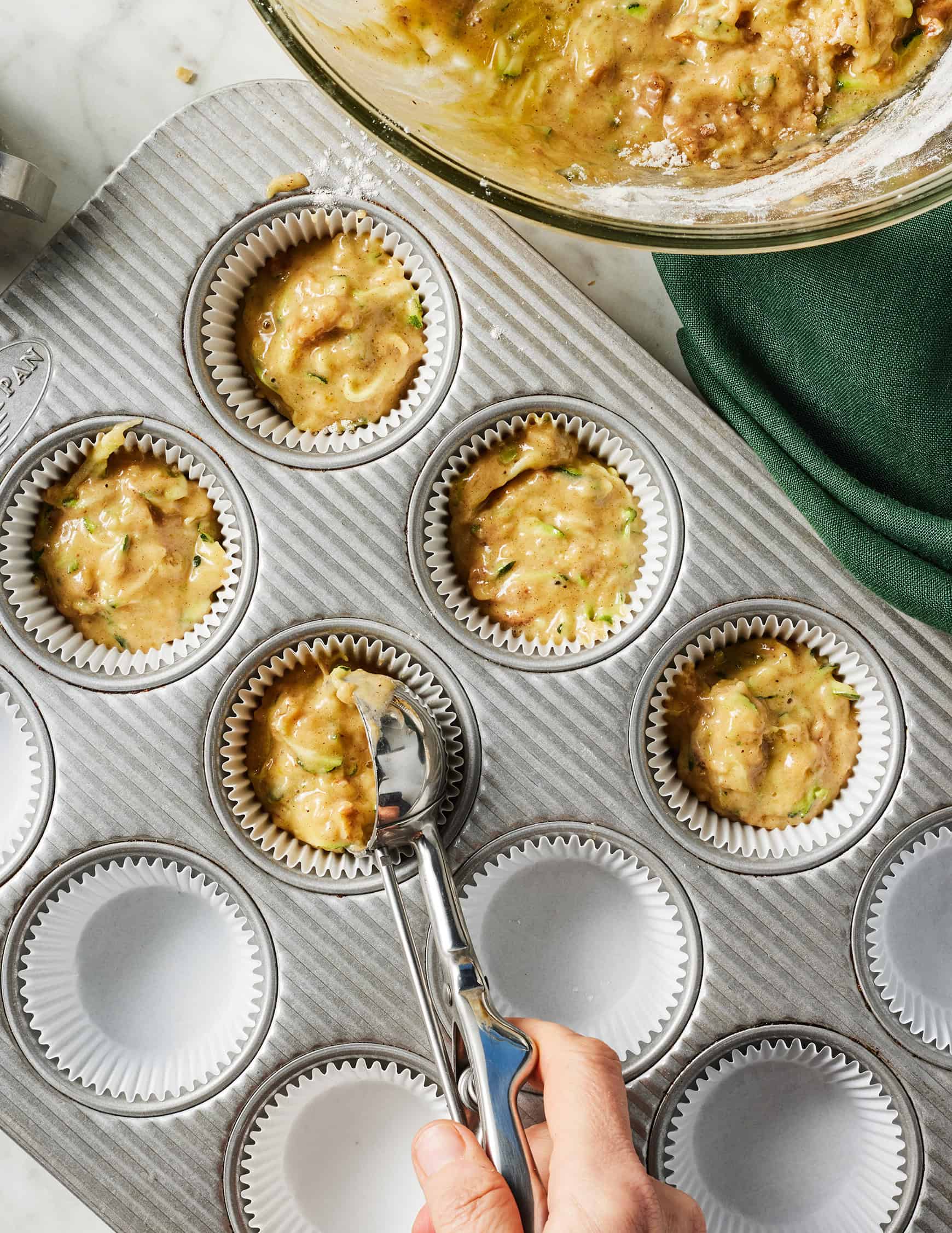 Scooping batter for zucchini muffins into muffin tin