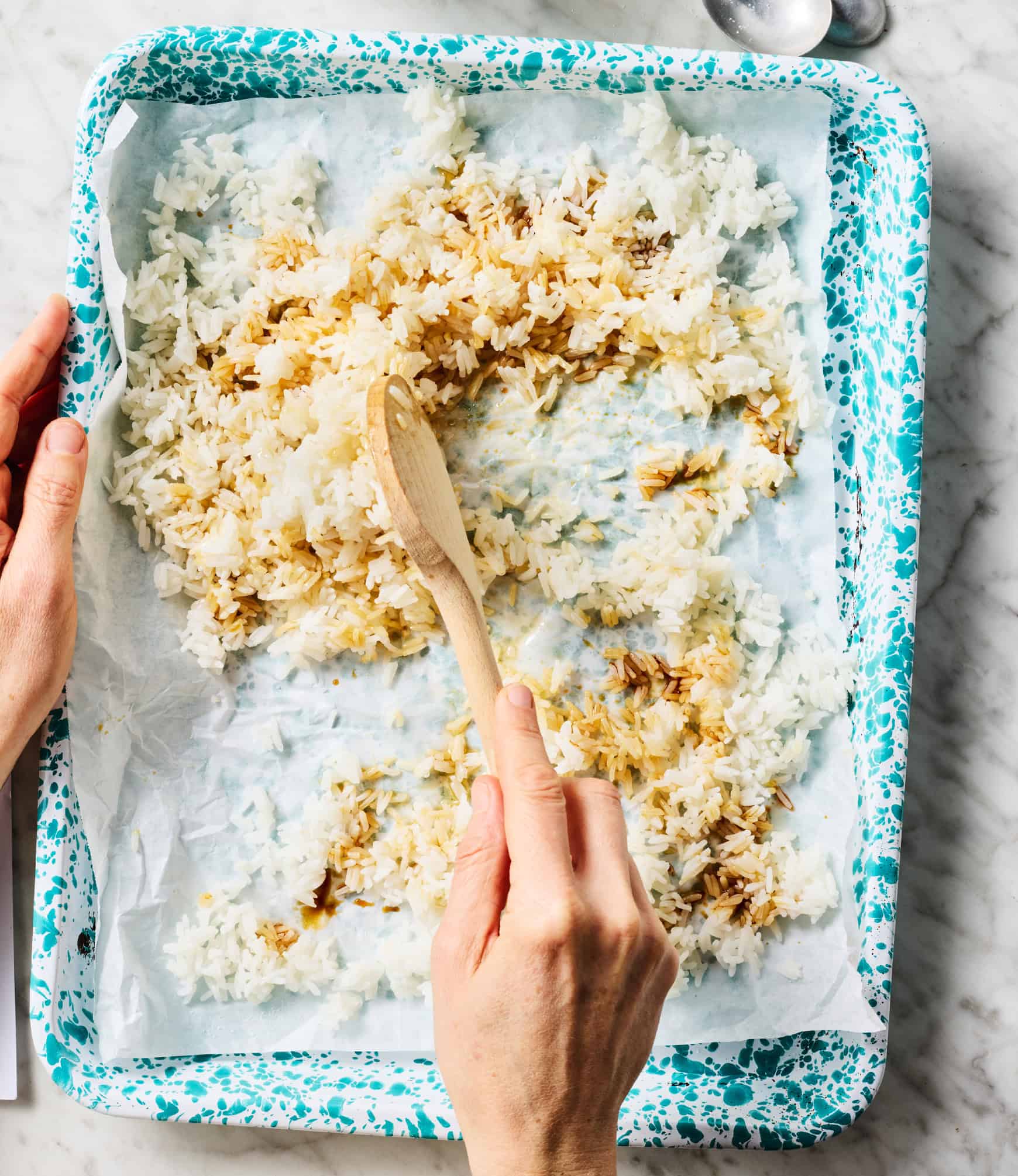 Tossing rice with soy sauce on baking sheet