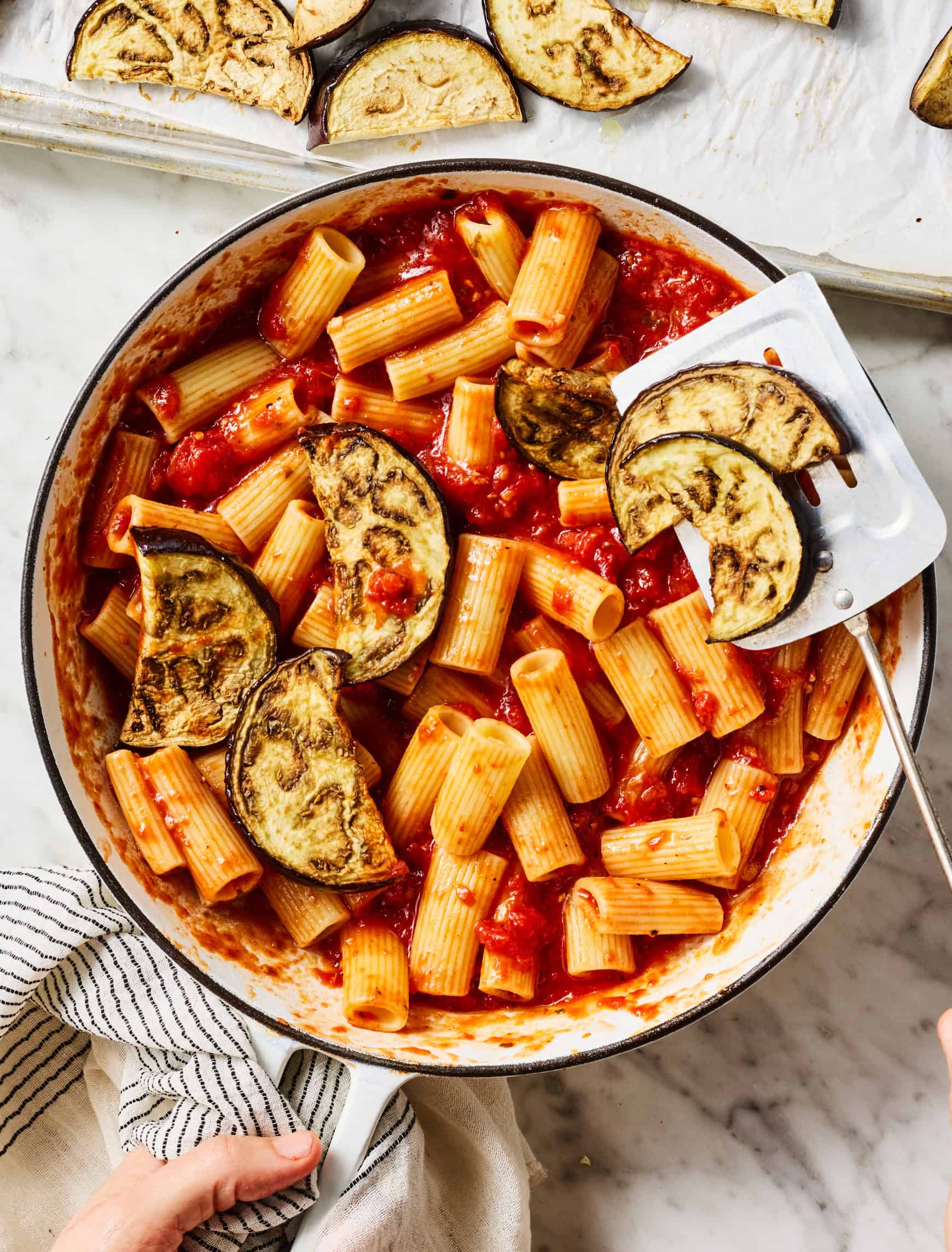 Adding roasted eggplant to skillet with pasta and tomato sauce