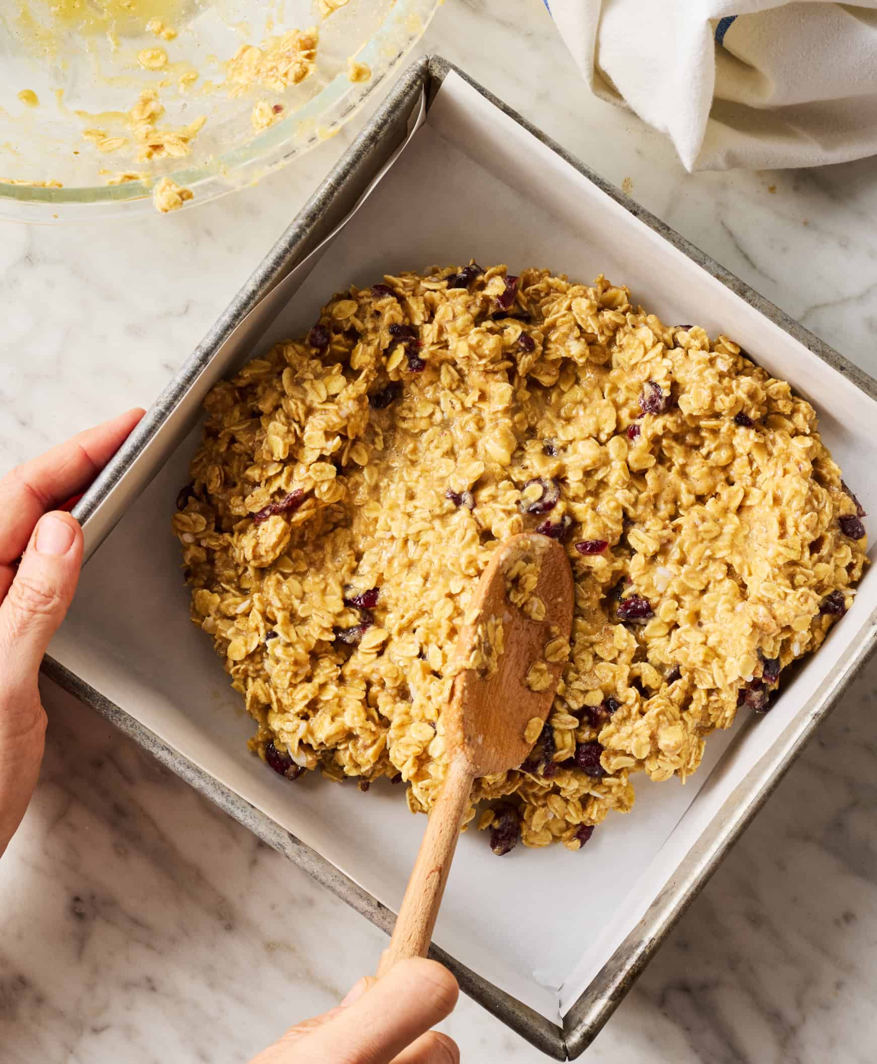 Spreading oat mixture in parchment-lined baking dish