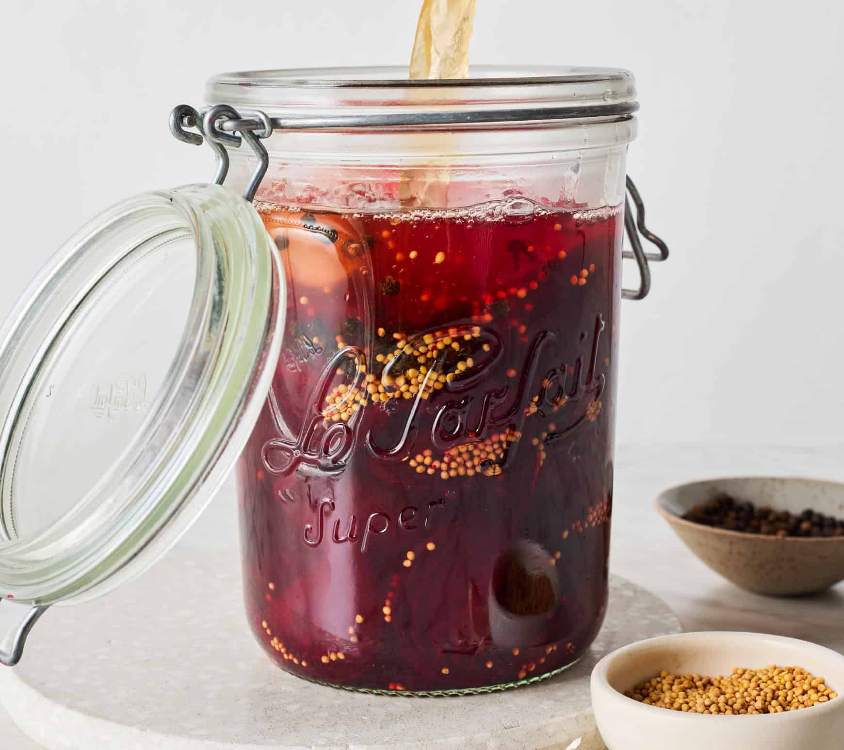 Pouring brine into jar with garlic, spices, and beets