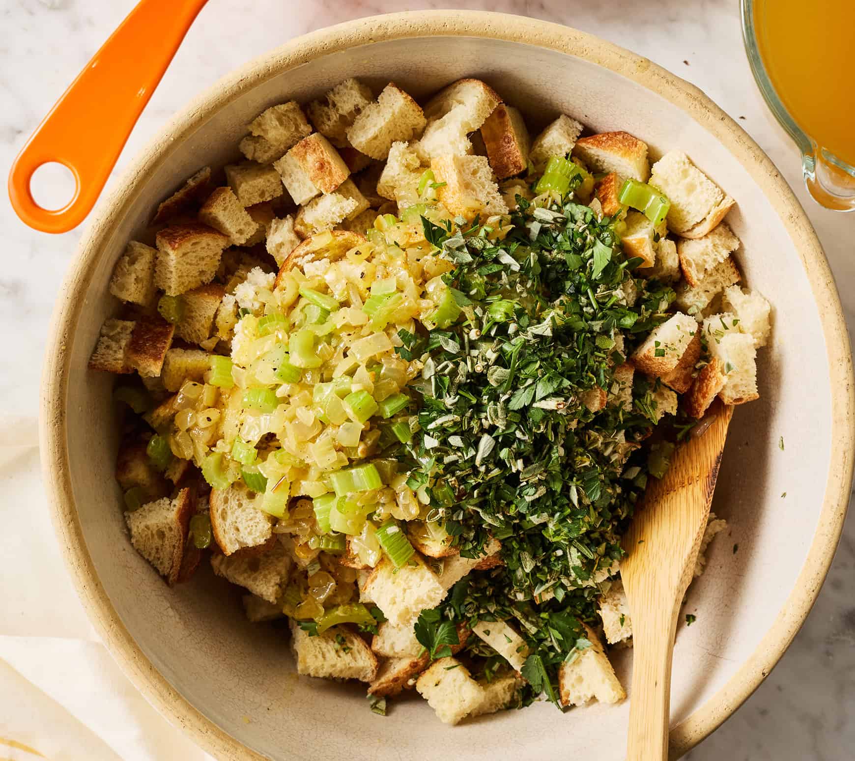 Dried bread cubes, celery, and herbs in mixing bowl