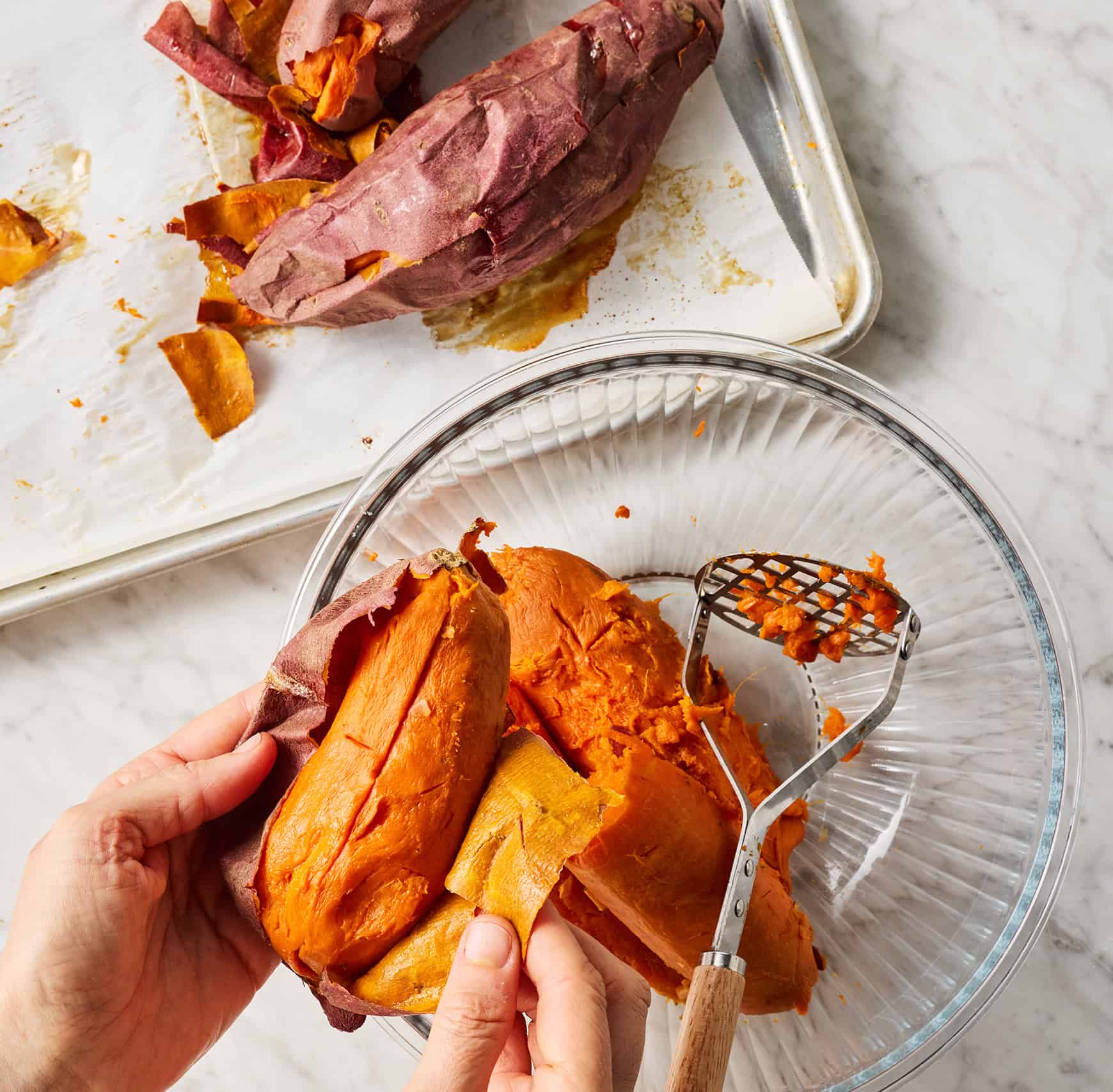 Peeling baked sweet potatoes and adding to bowl with potato masher