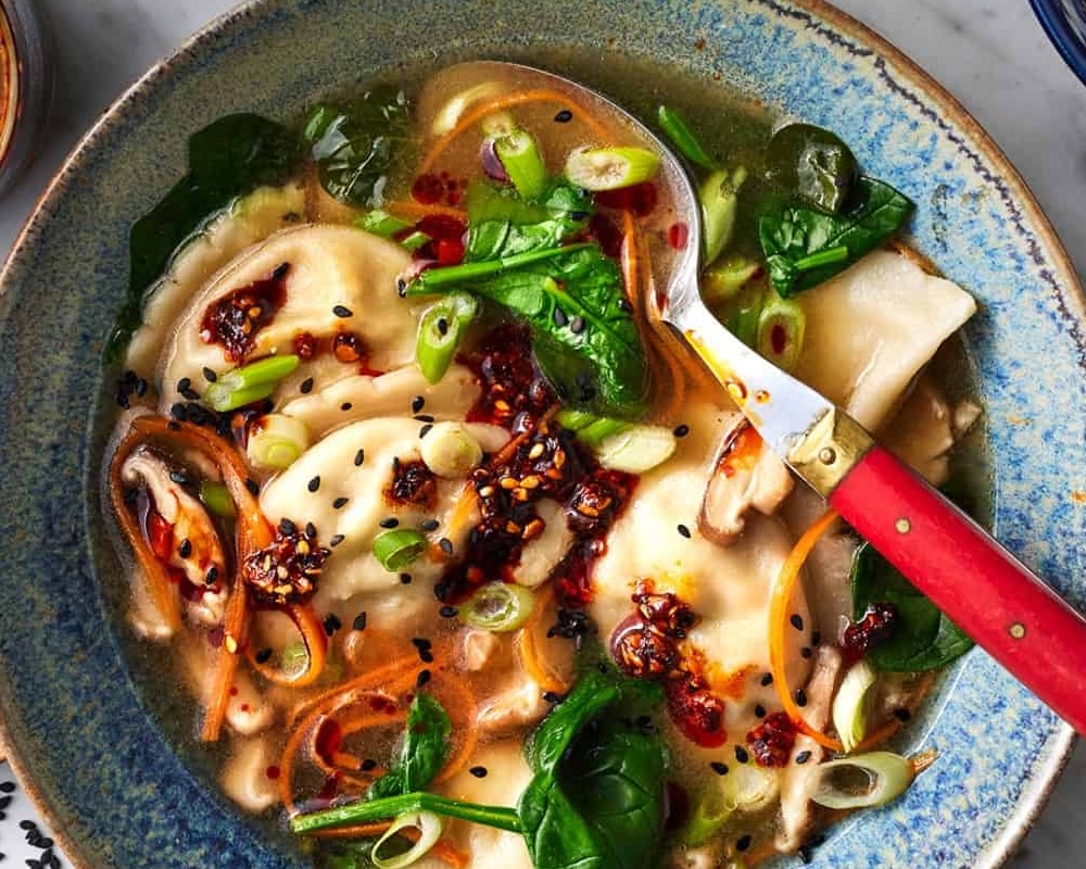 Bowl of dumpling soup with red spoon